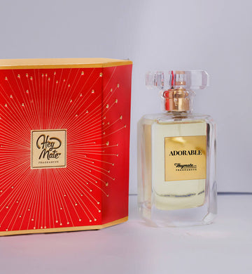 Perfume bottle labelled 'Adorable' by Hey Mate Fragrances next to its red packaging box.