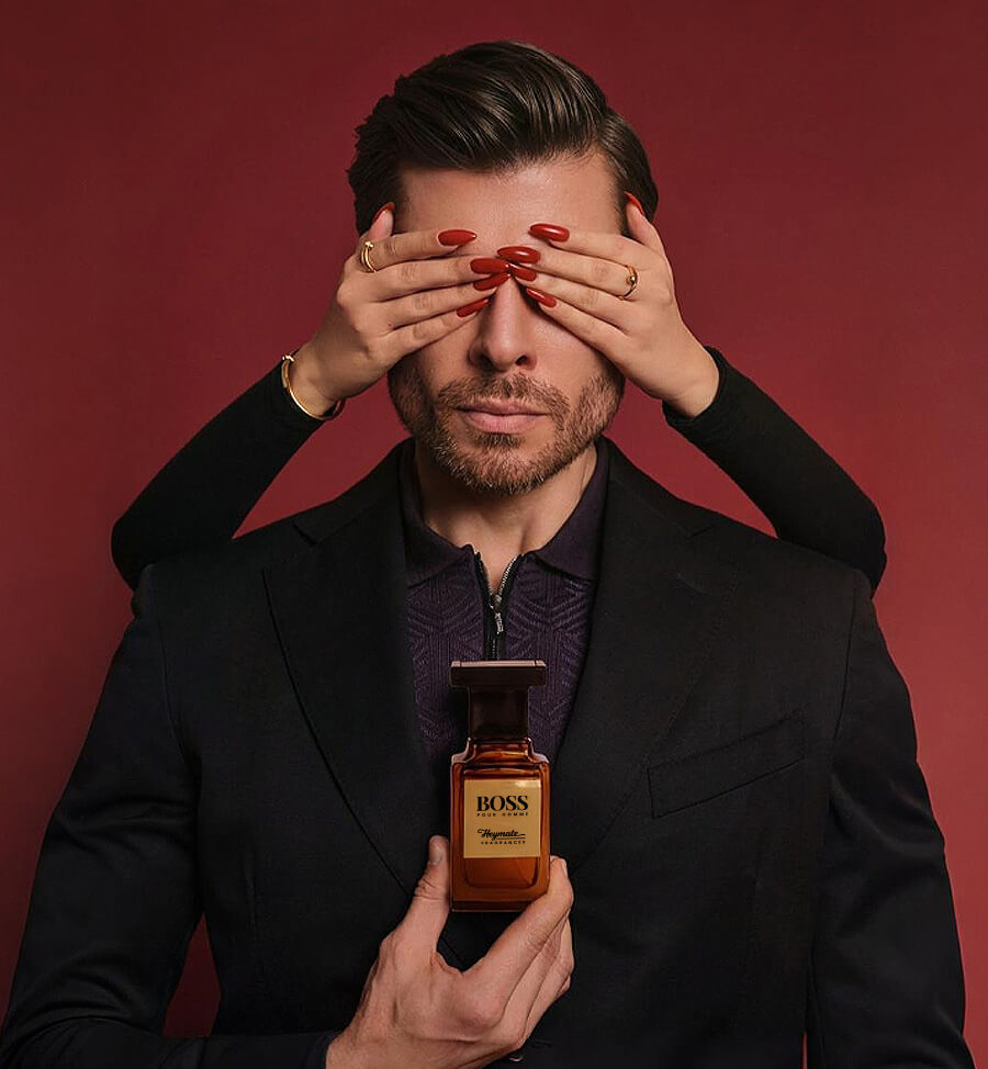 Man holding a BOSS perfume bottle with a red background