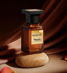 Perfume bottle labeled 'Majestic' by Heymate Fragrances on a stone surface with a draped fabric background.